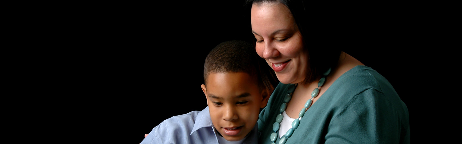 mother and son reading with a black background