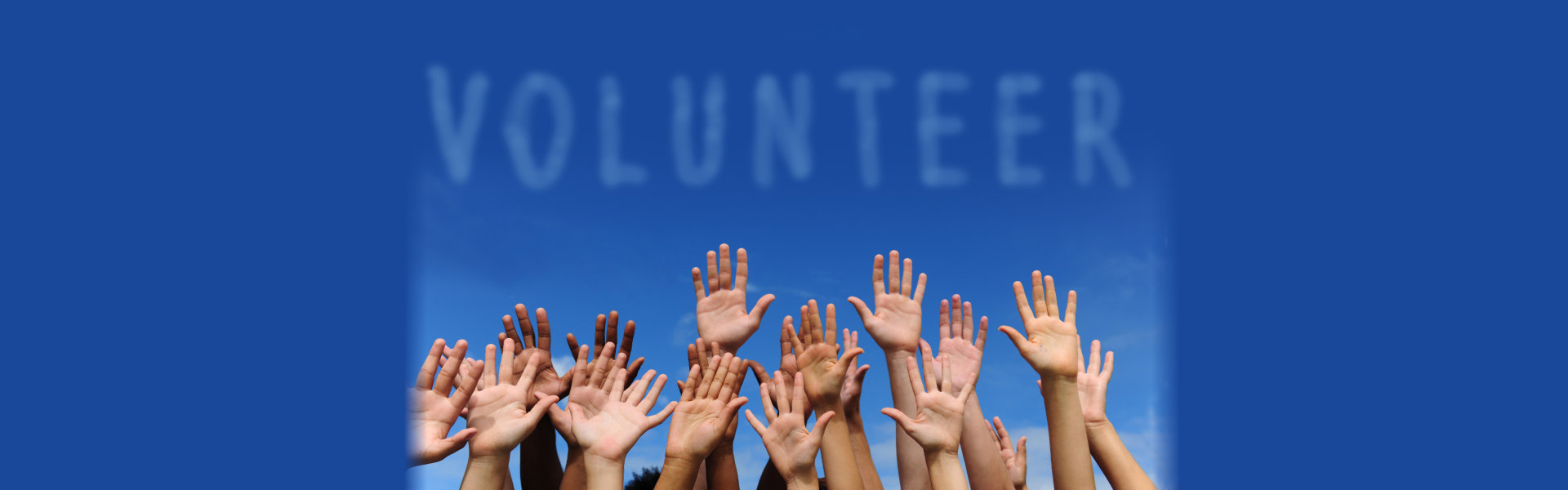 a group of hands raised in the air with clouds formed volunteer word
